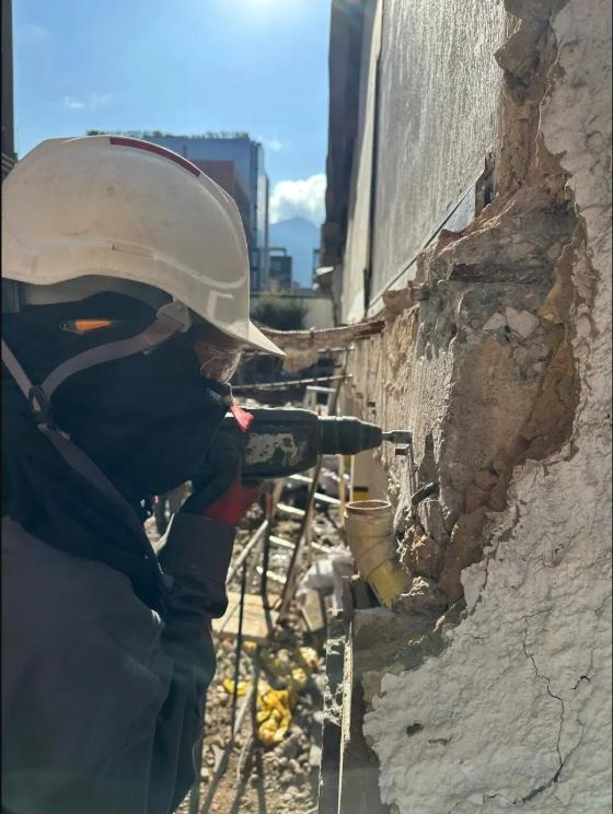 Trabajador retirando revoque deteriorado de una fachada con taladro