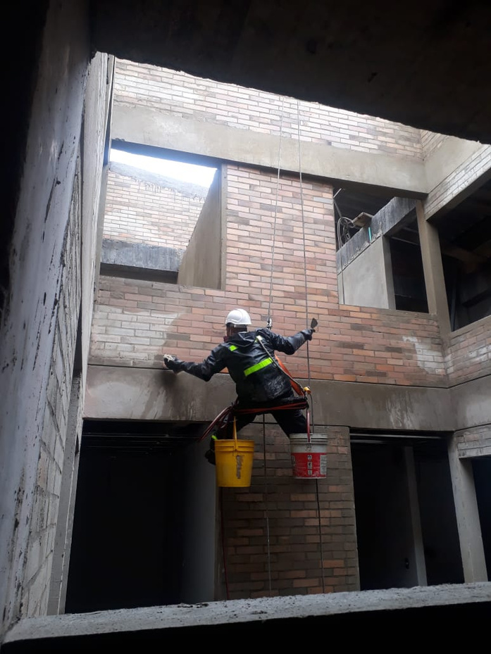 Técnico certificado trabajando en rapel sobre fachada en ladrillo